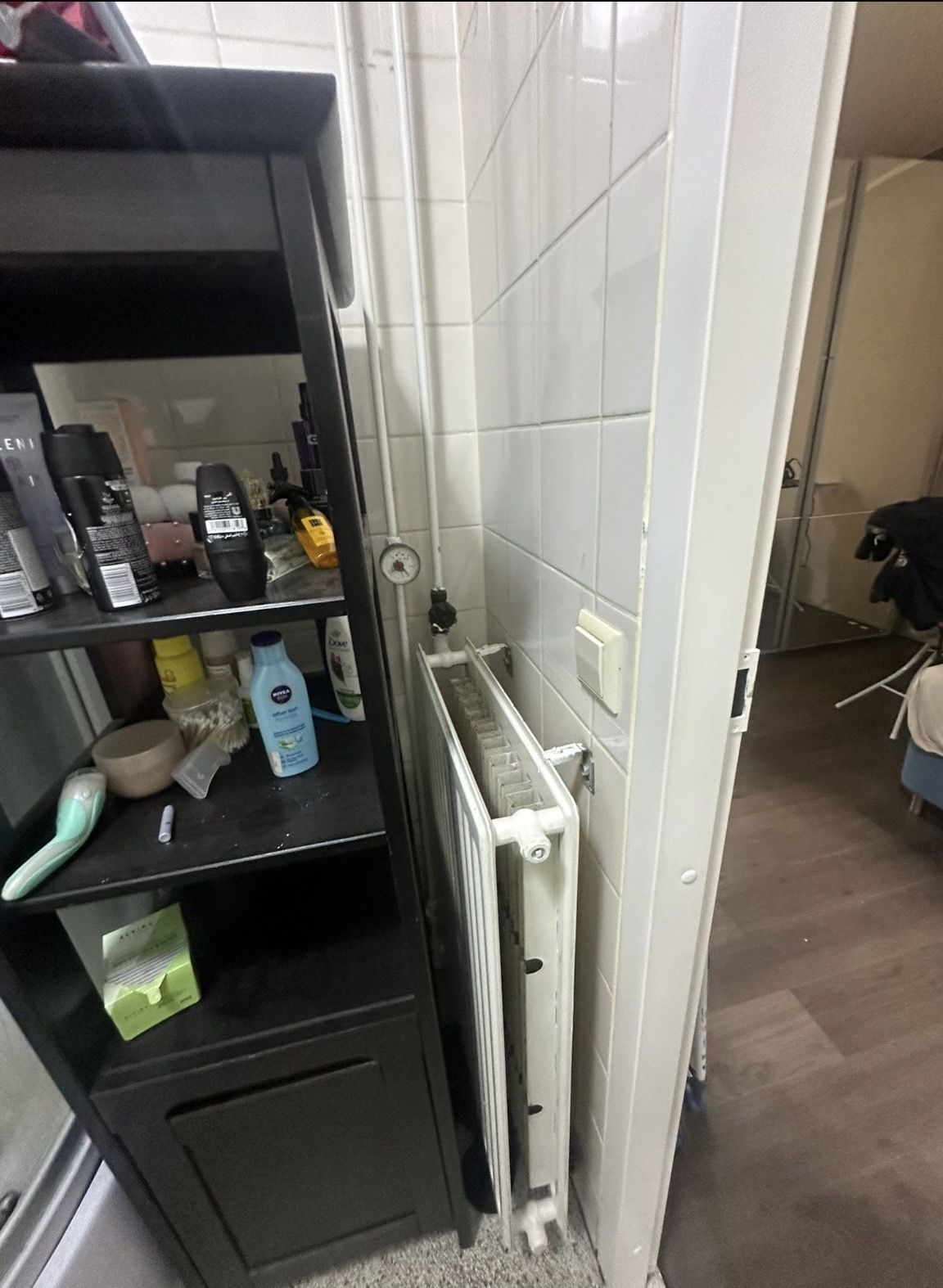 Renovatie woning Zaanstreek: De oude badkamer: opbouwleidingen en een radiator tegen de tegels