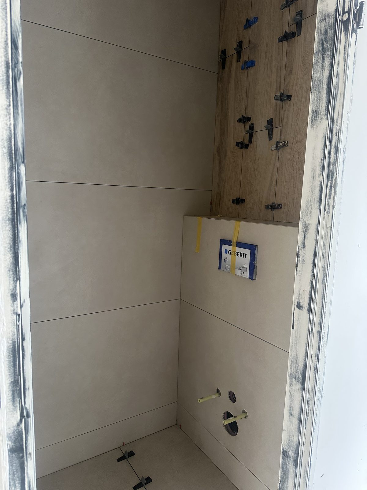 Wand en vloer betegeld, houtlook achter het toilet